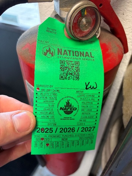 Wall-mounted fire extinguisher with inspection tag